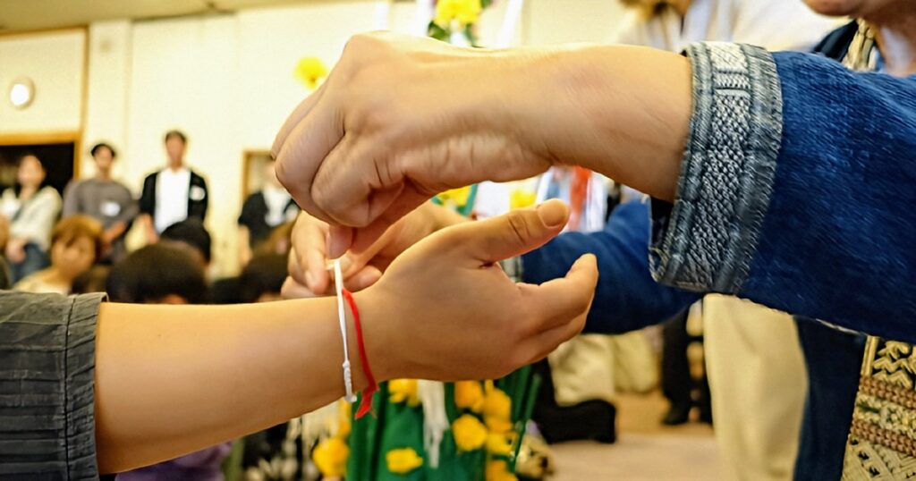 祝福や無病息災を祈りながら、お互いに糸を巻き付ける様子